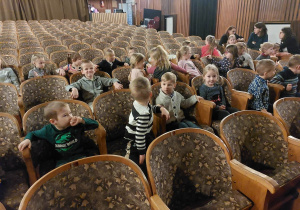 dzieci siedzą na krzesłach w teatrze