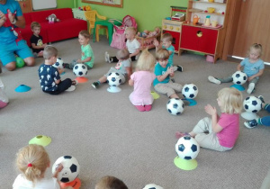 dzieci siedzą na dywanie z piłkami