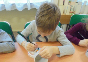 chłopiec maluje kubek