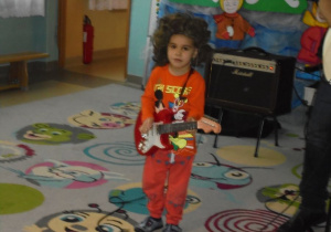 chłopiec w peruce gra na gitarze