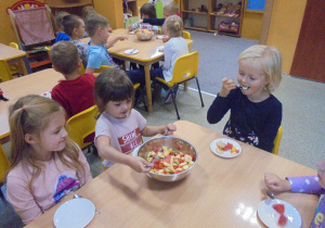 dzieci częstują się sałatką owocową