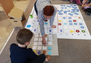 Dzieci i nauczycielka bawią się z pomocą maty do kodowania