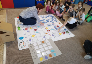Dzieci i nauczycielka bawią się z pomocą maty do kodowania